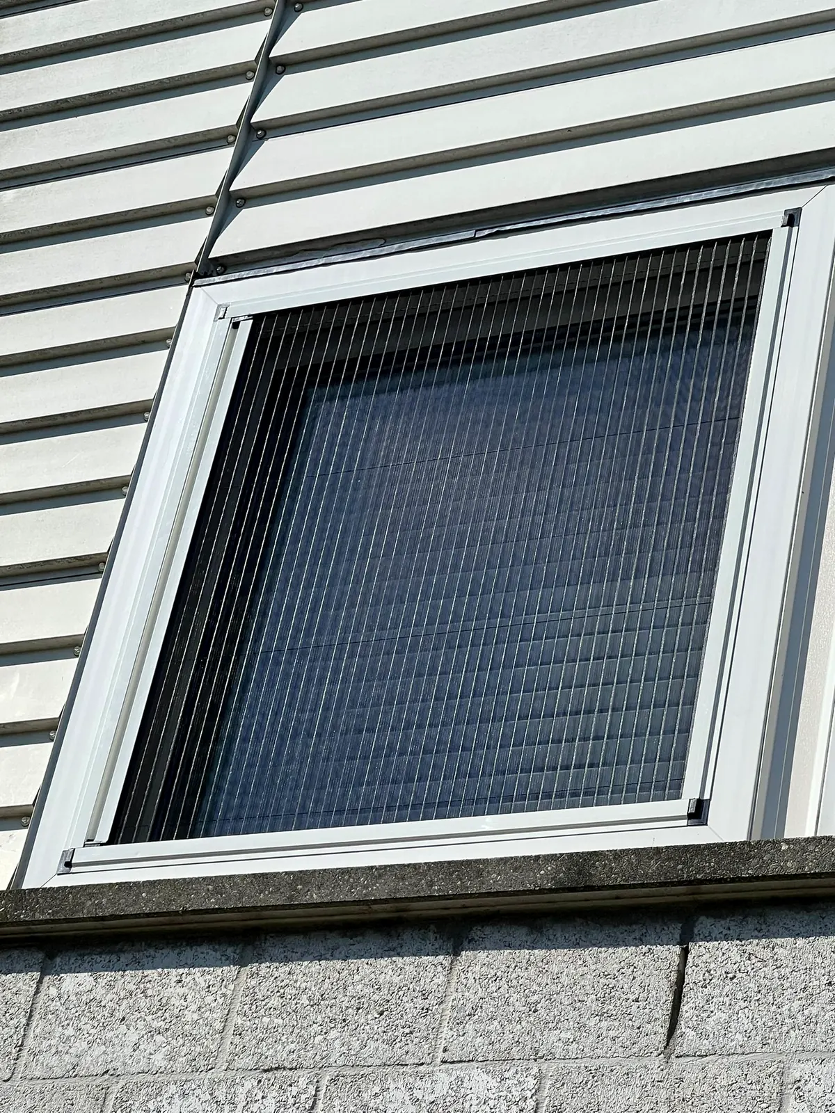 Fenster mit Fliegengitter in einer Holzfassade